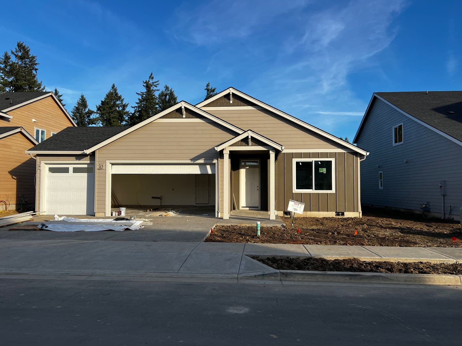 Single-story craftsman ranch home with tan siding, covered porch, and attached garage