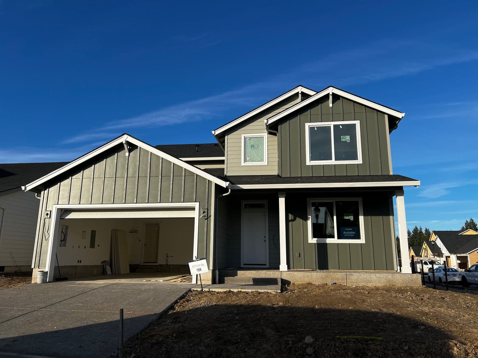 Two-story home with dark olive board-and-batten siding and attached garage