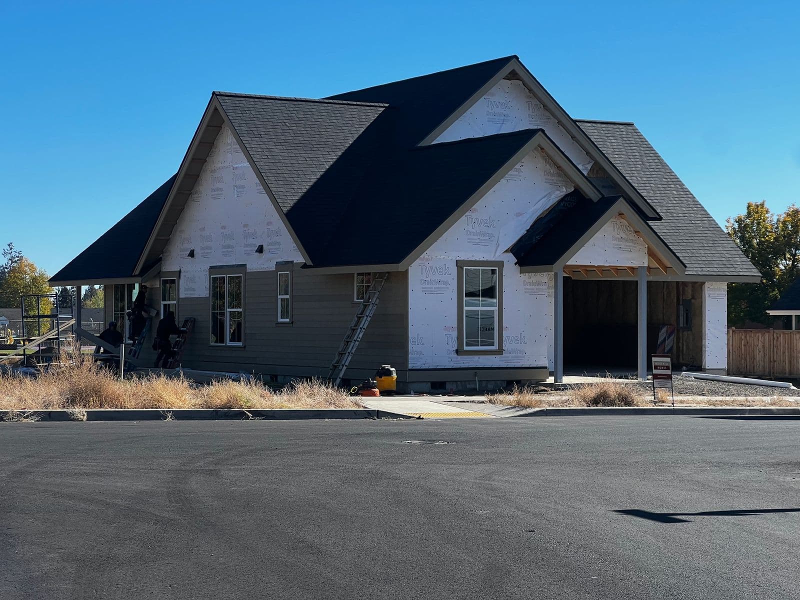 Ranch-style home mid-construction with siding installation over house wrap